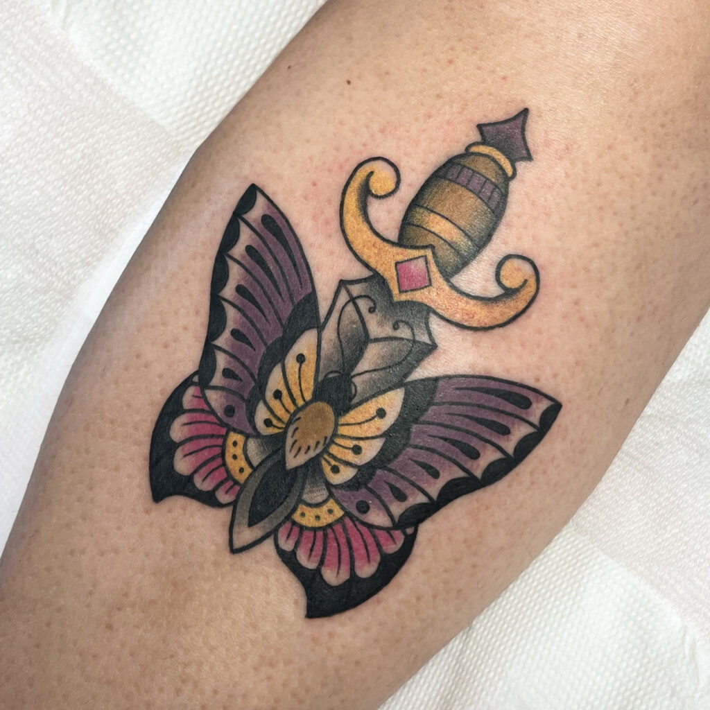 Tatouage style traditionnel en couleurs d'un papillon traversé par une dague