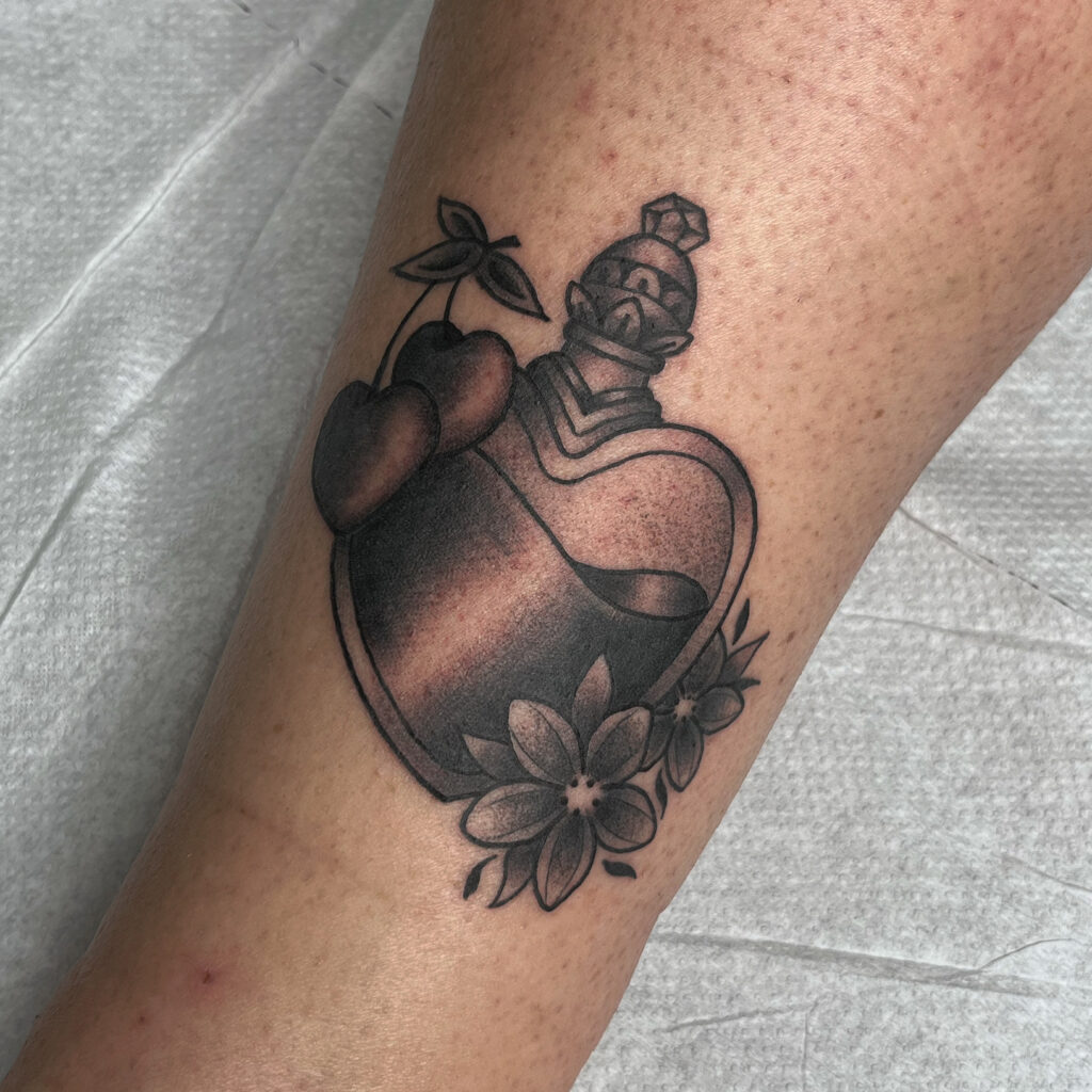 Tatouage style traditionnel en noir et gris d'une potion de filtre d'amour