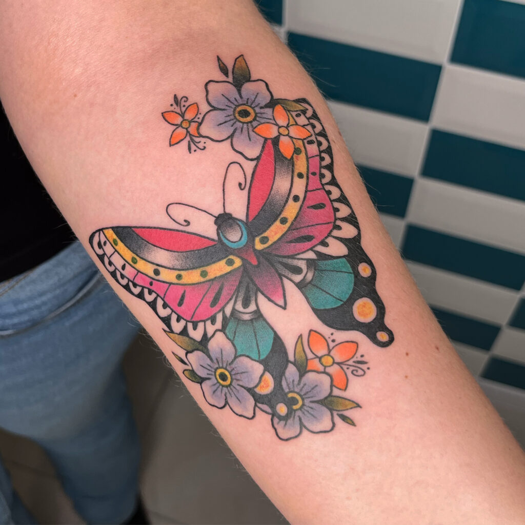 Tatouage style traditionnel en couleurs d'un papillon avec des fleurs